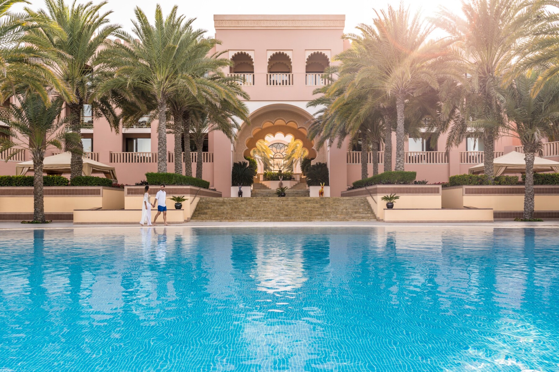 Pool und palmenbestandene Fassade des Al Husn Hotel Muscat am Nachmittag