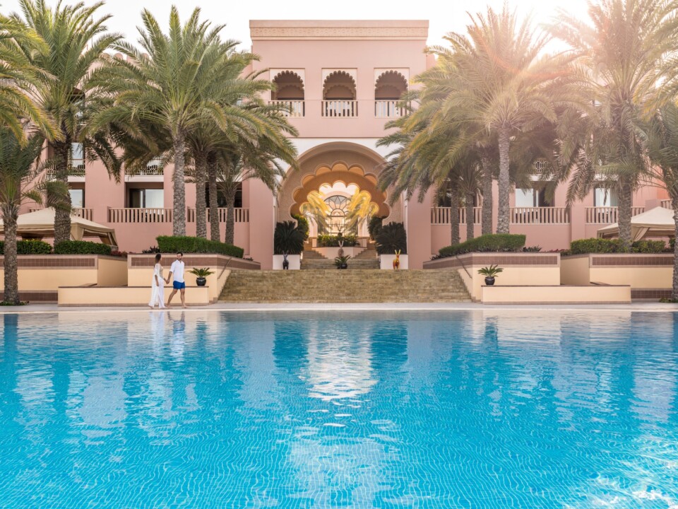 Pool und palmenbestandene Fassade des Al Husn Hotel Muscat