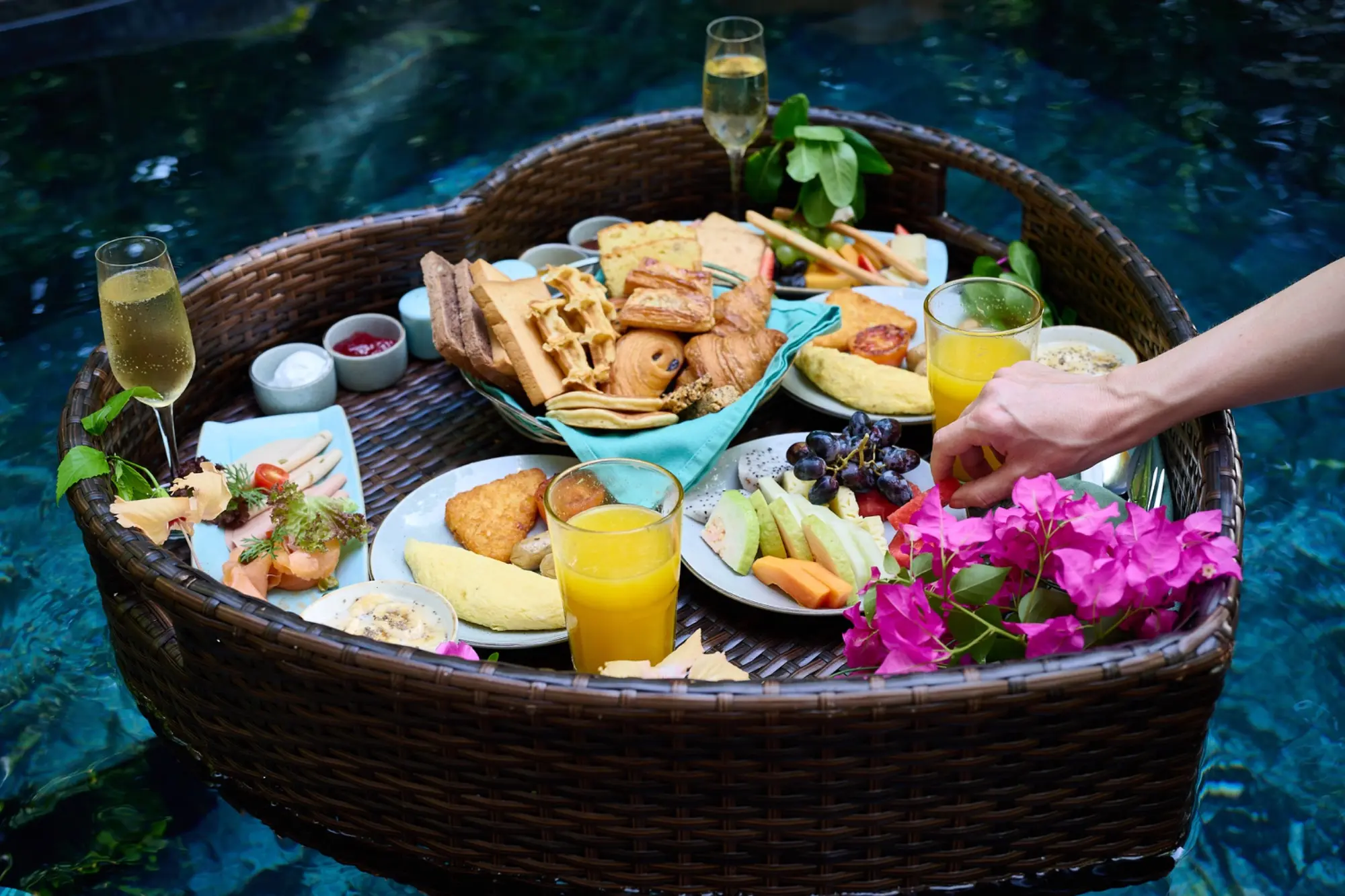Ein reich gedecktes Floating Breakfast mit Obst, Gebäck, Säften und Kaffee schwimmt im Pool.