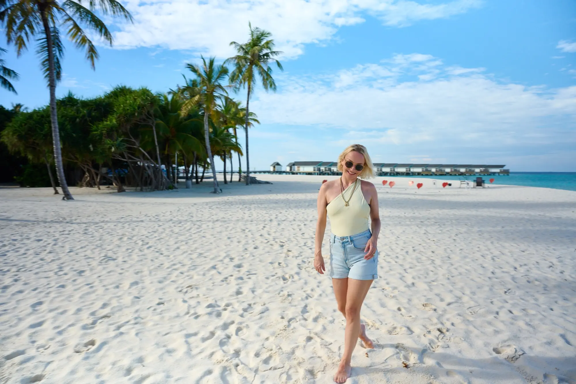 Janin Ullmann läuft bei Sonnenschein über den weißen Strand von RAAYA.