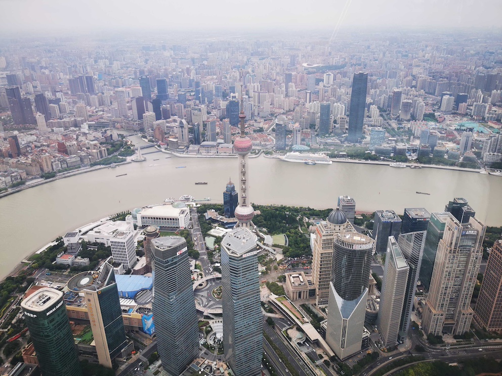 Luftaufnahme der Skyline von Shanghai, die den Huangpu-Fluss, den Oriental Pearl Tower und umliegende Wolkenkratzer zeigt, aufgenommen vom Shanghai Tower.