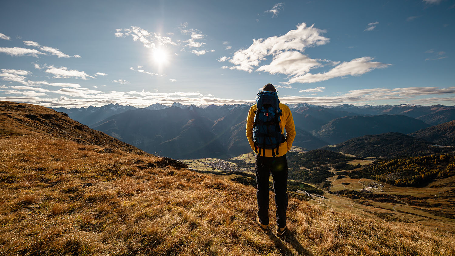 Weite Bergwelt mit einem Wanderer davor.