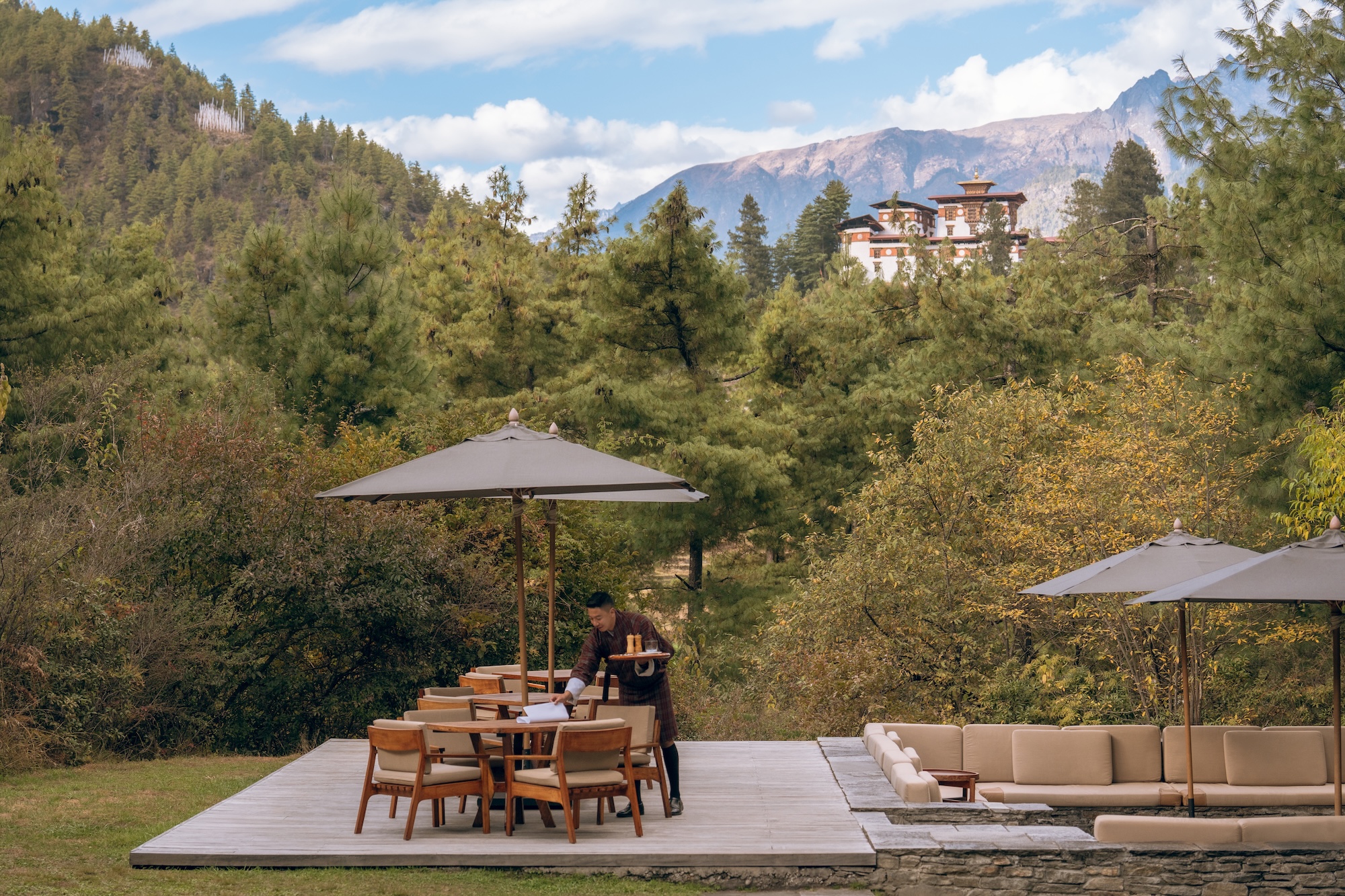 Terrasse der Amankora Paro Lodge mit Blick über Kiefern und Berge zur Festung Drukgyel Dzong.