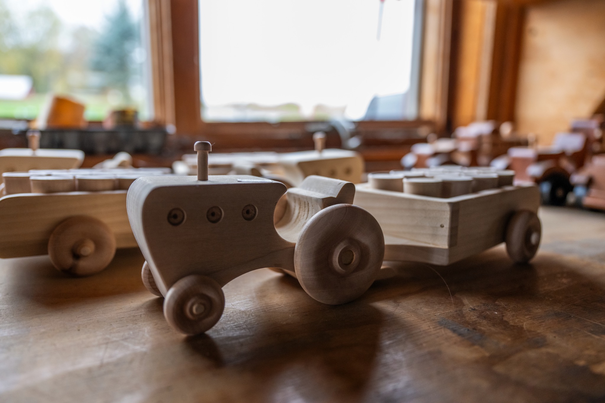 Handgefertigte Spielzeugfahrzeuge aus Holz auf einem Tisch in einer Werkstatt.