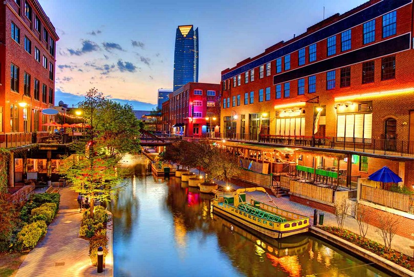 Blick auf den Bricktown Canal mit Wassertaxi und Restaurants zwischen Backsteingebäuden