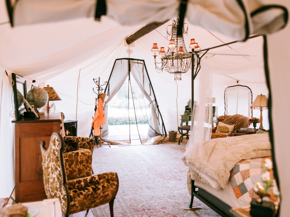 Möbliertes Glamping-Zelt der Depot Lodge mit Bett, Sessel und Kronleuchter