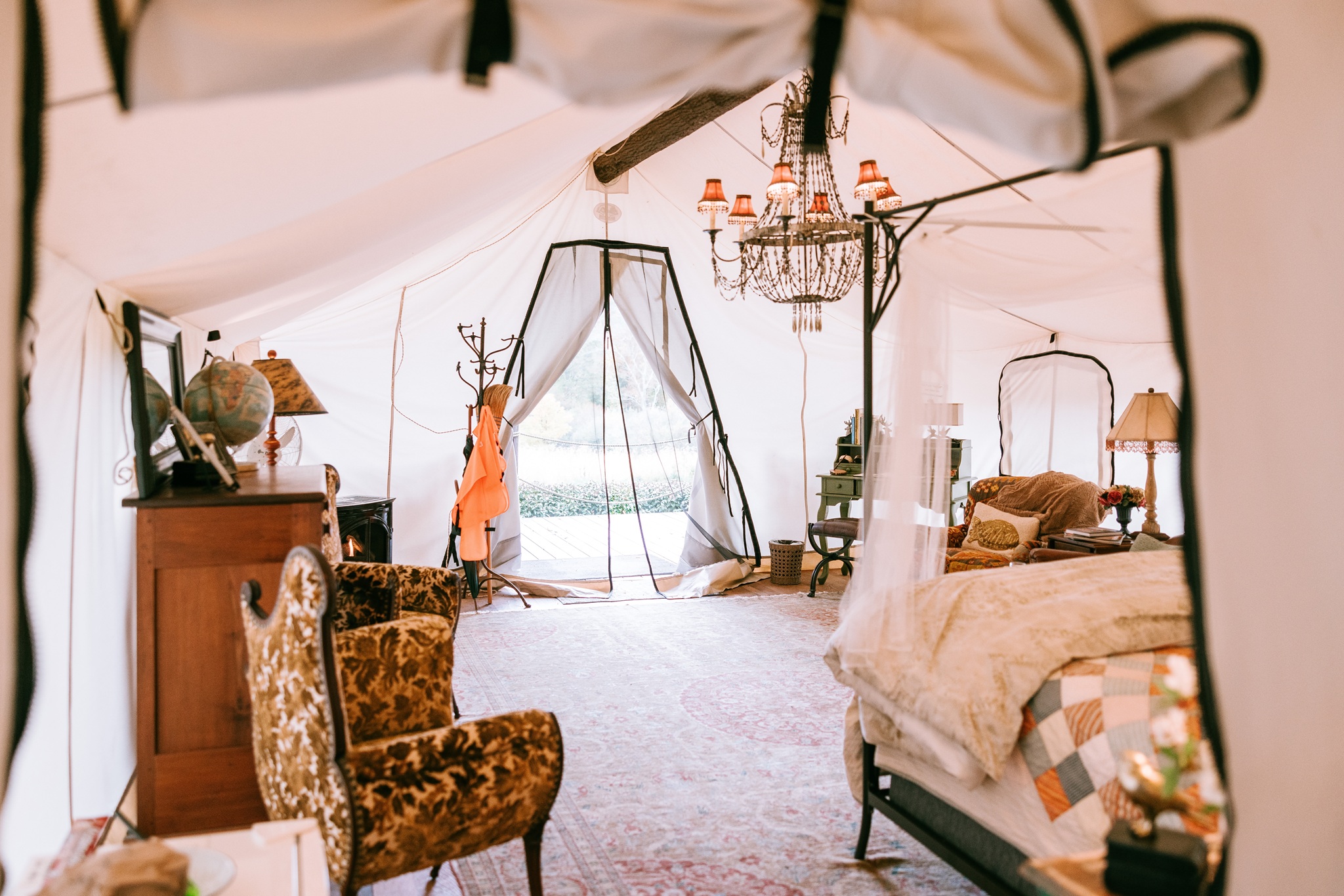 Möbliertes Glamping-Zelt der Depot Lodge mit Bett, Sessel und Kronleuchter