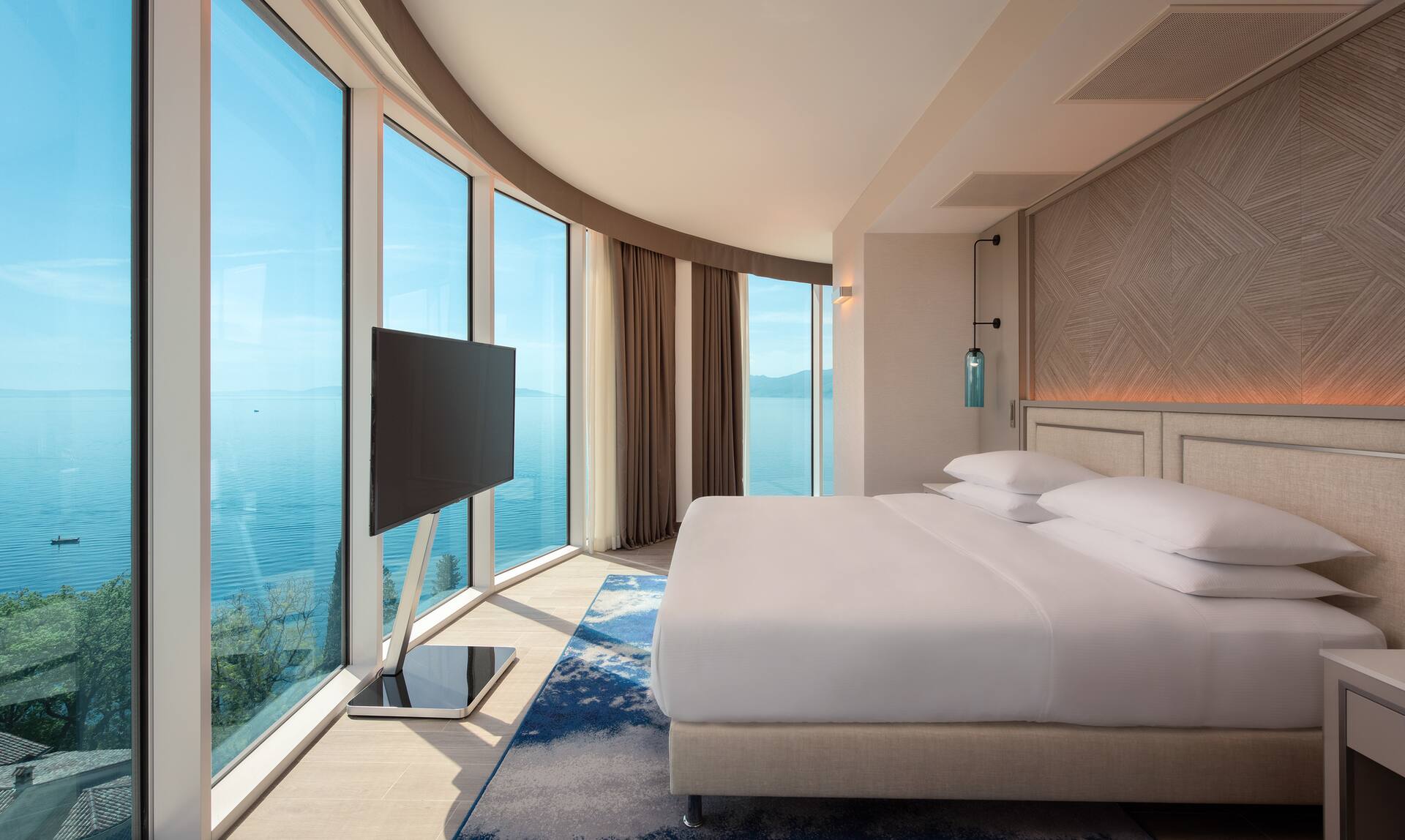 Schlafzimmer der Panorama-Suite mit breiter Fensterfront und Blick auf die Adria.