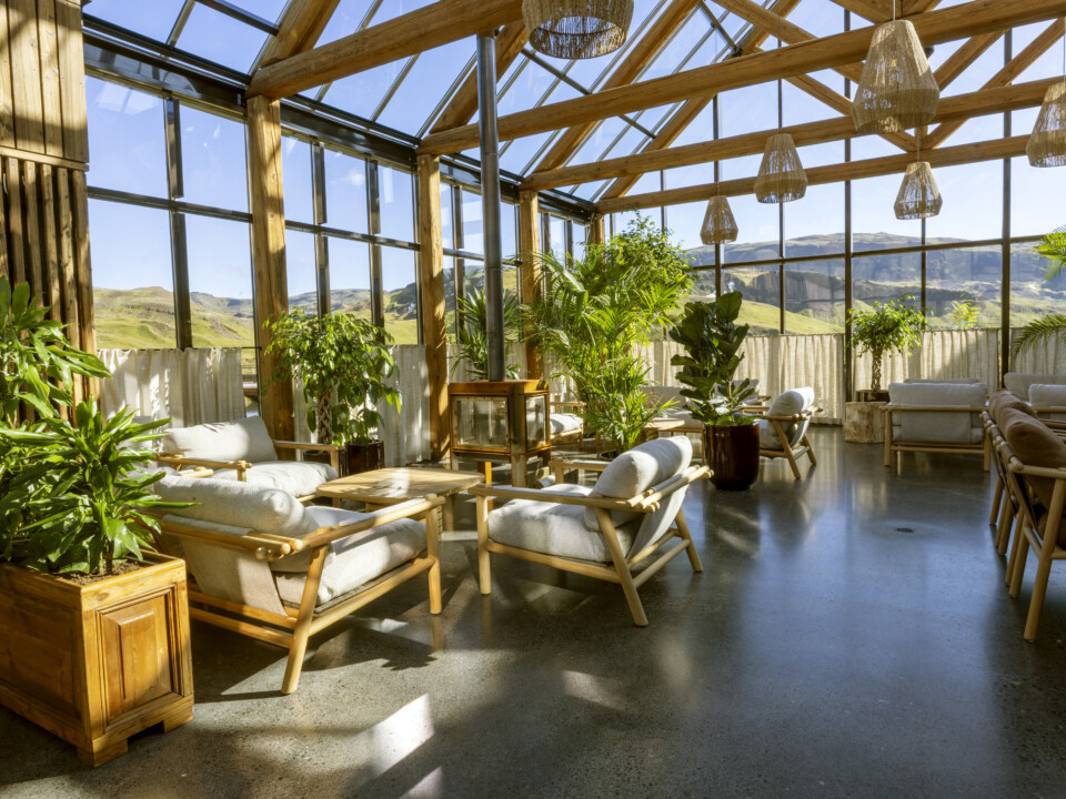 Lounge im Badehaus mit Pflanzen, Sesseln und großen Fenstern