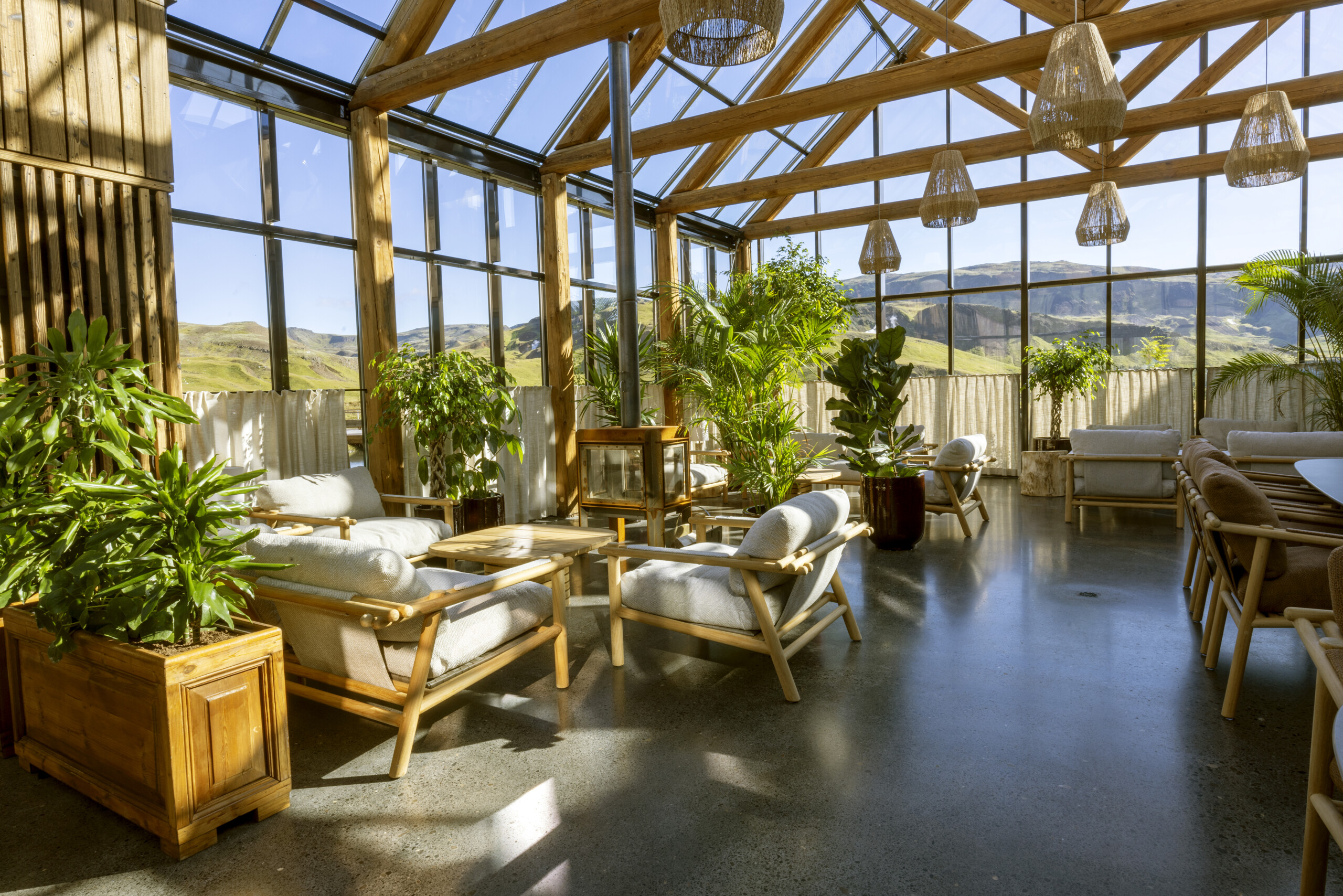 Lounge im Badehaus mit Pflanzen, Sesseln und großen Fenstern