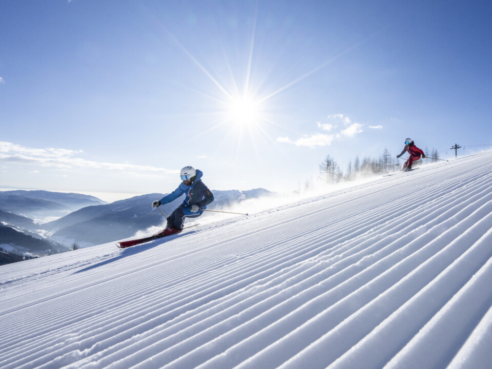 Skifahrer auf einer präparierten Piste in Bad Kleinkirchheim vor verschneiten Bergen.
