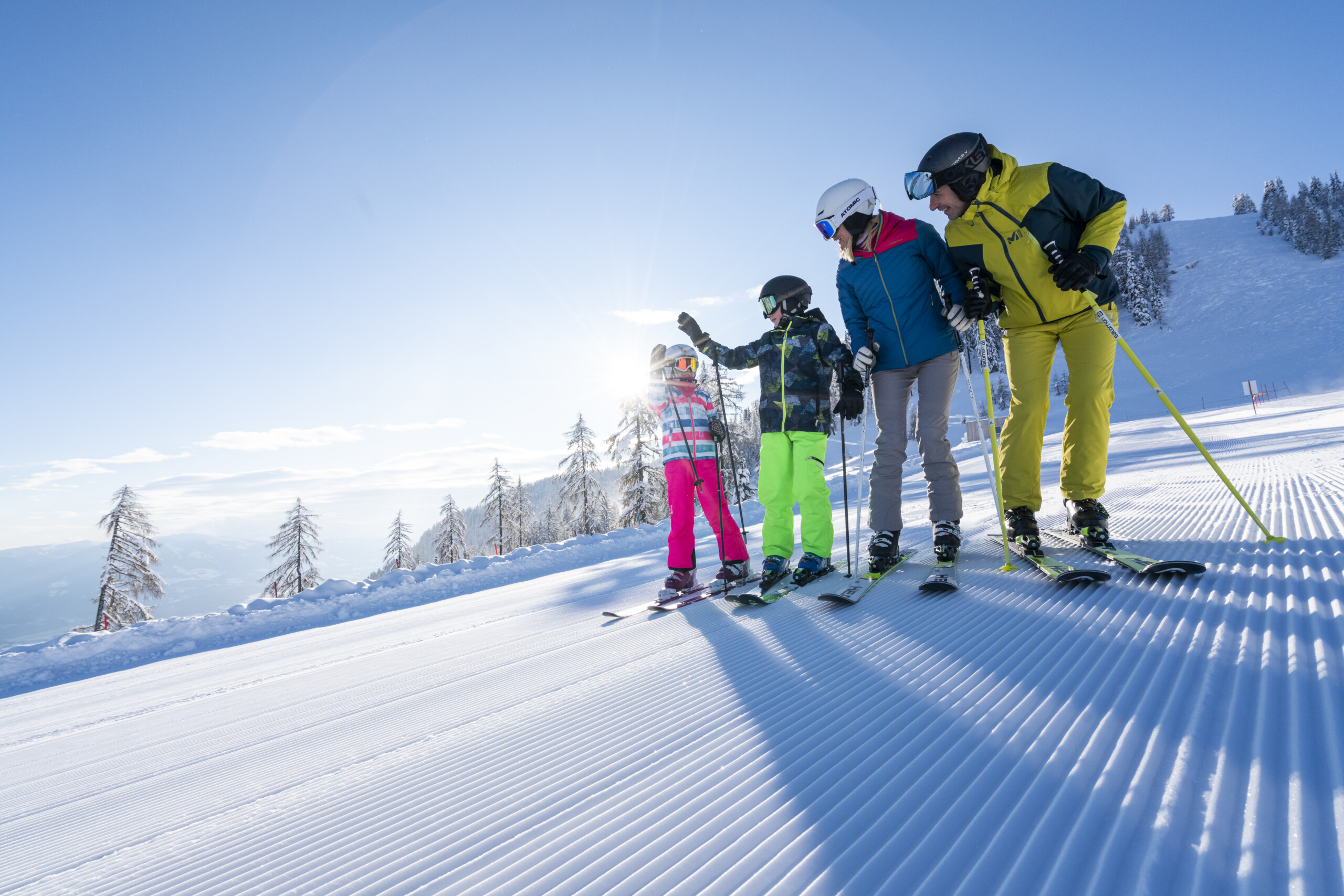 Familie mit Skiern auf einer sonnigen Piste am Sportberg Goldeck.