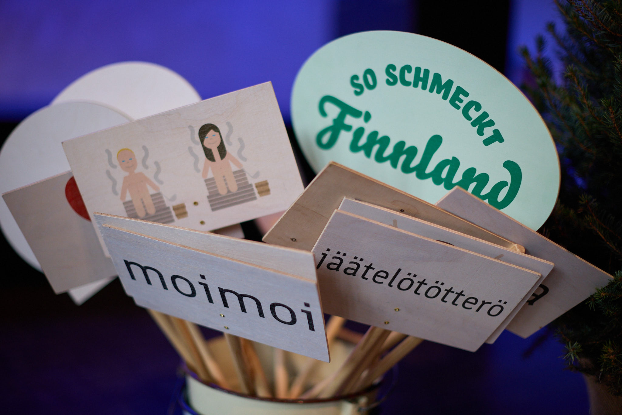 Schilder mit der Aufschrift So schmeckt Finnland, finnischen Wörtern und einer Sauna-Illustration.