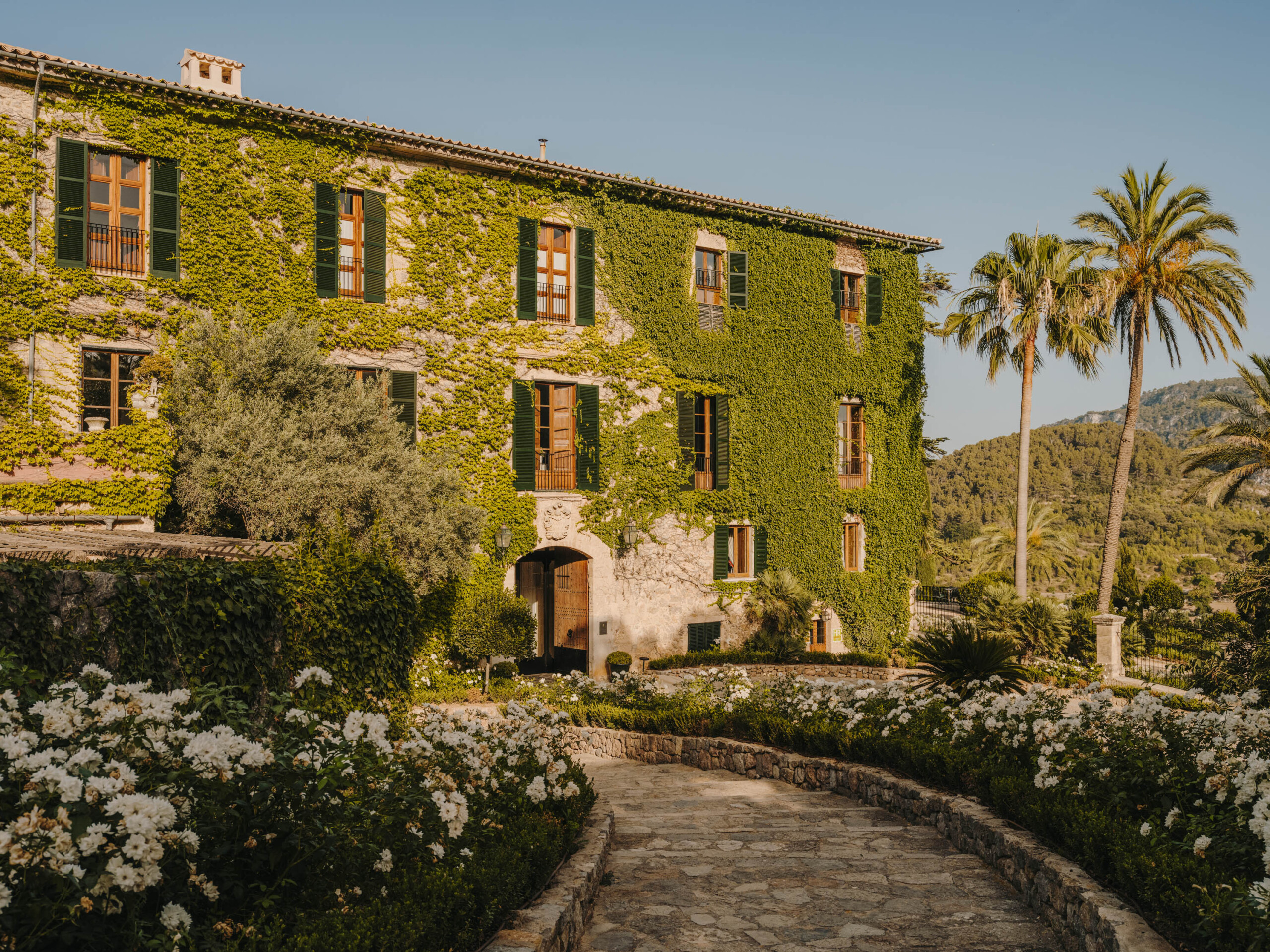 Bewachsene Fassade des Grand Hotel Son Net mit grünen Fensterläden und mediterranem Garten
