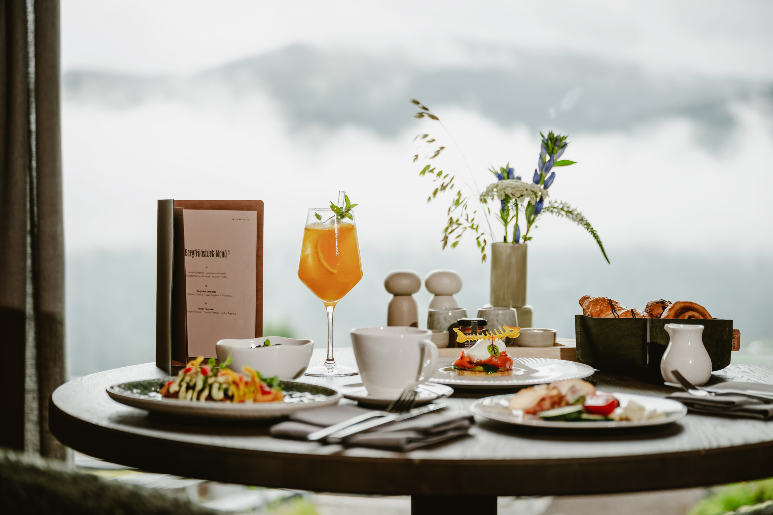 Frühstückstisch in der Stube 3 mit Brotkorb, verschiedenen Gerichten und Ausblick durch das Fenster