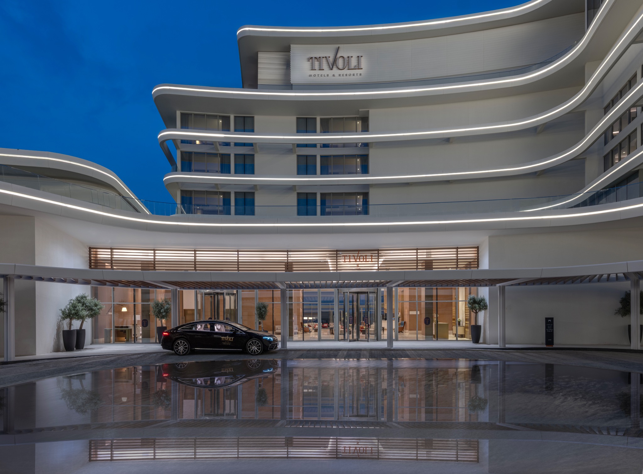 Eingangsbereich und geschwungene Fassade des Tivoli LA VIE Muscat am Abend